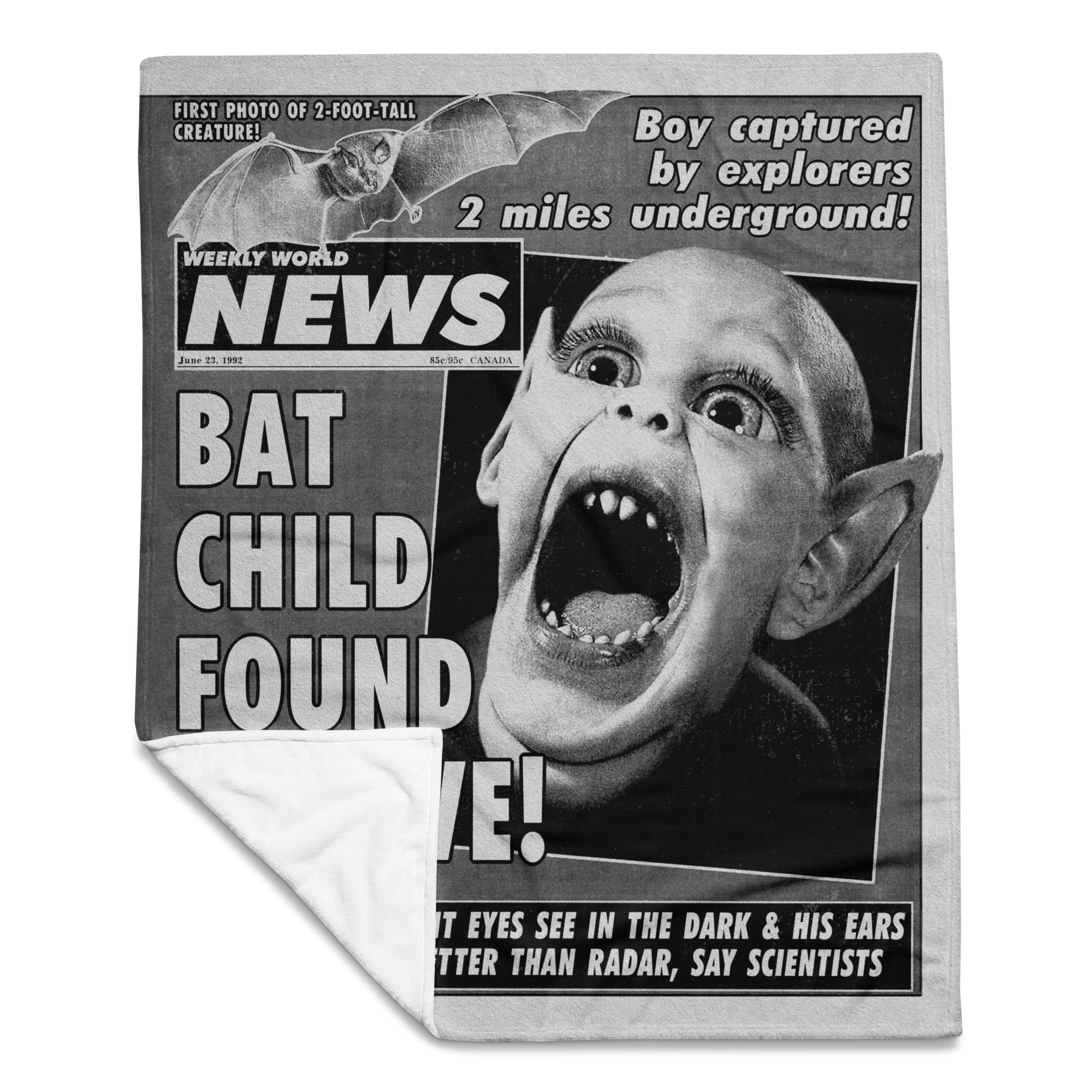 Blanket with a vintage newspaper design featuring a creature and headlines.